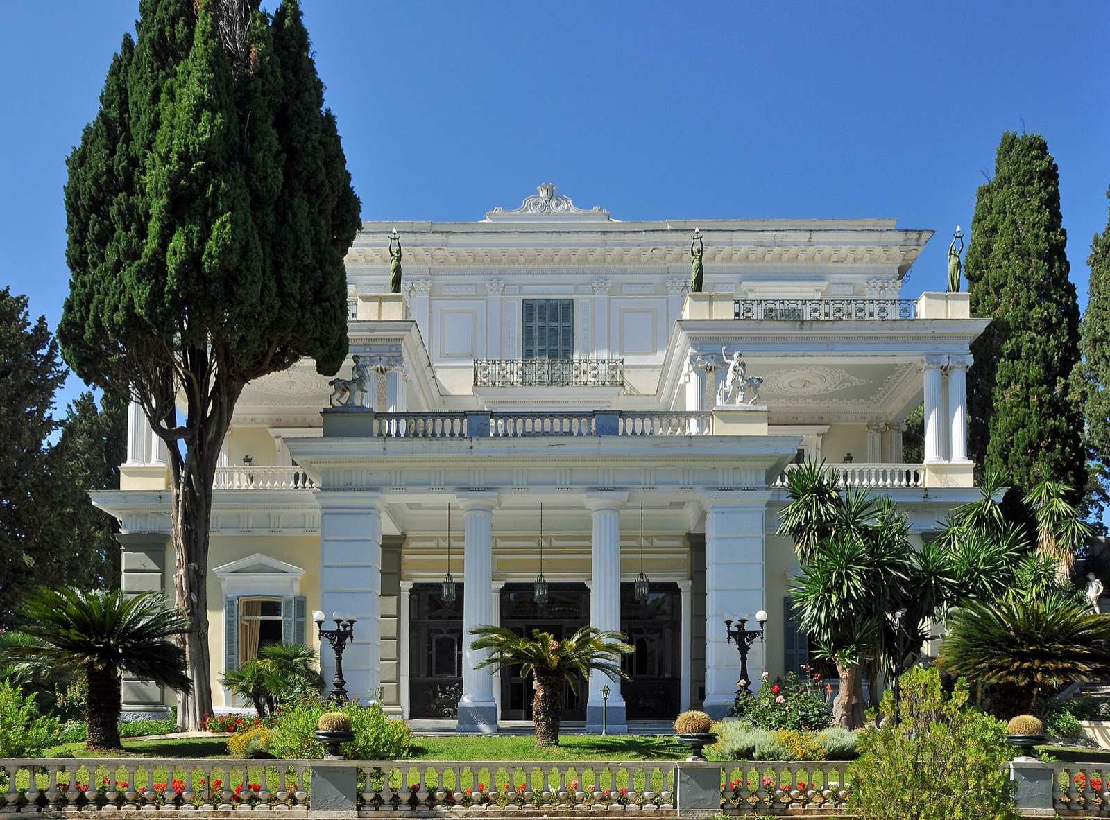 Achilleion Palace facade with cypress trees and Ionian-blue sky